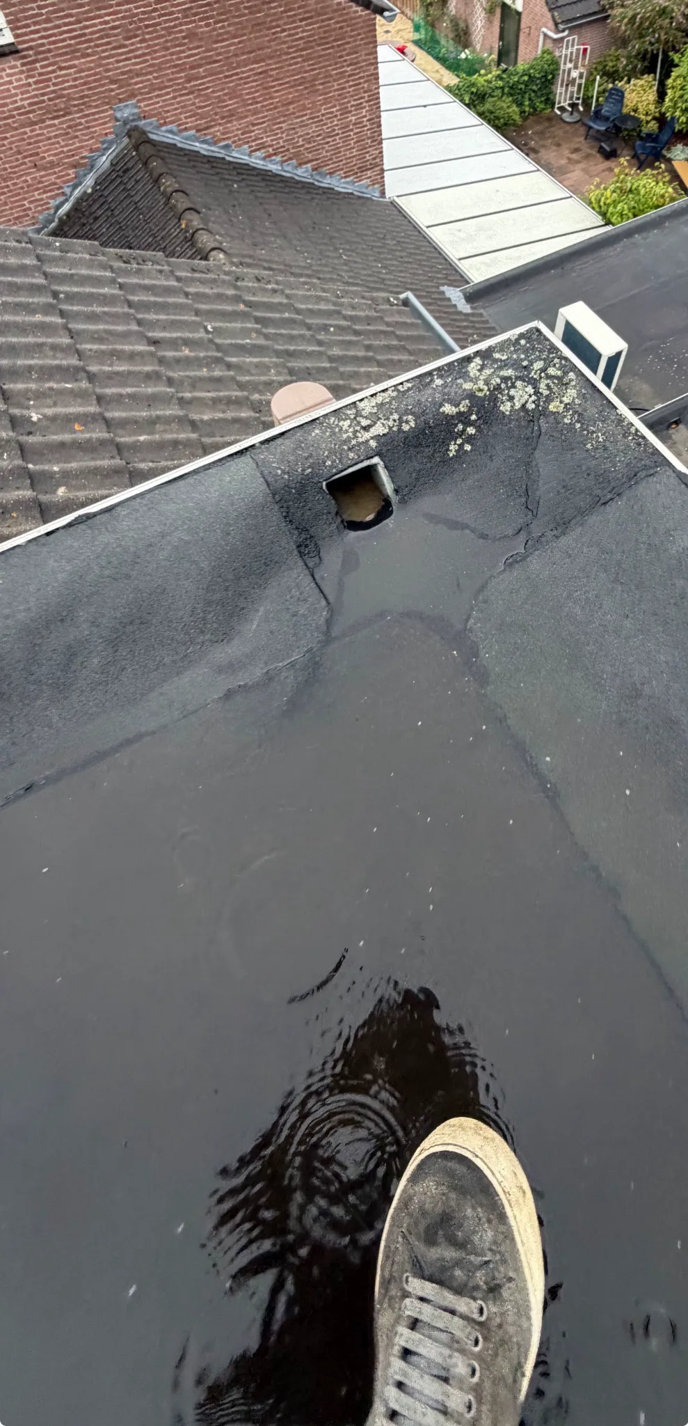 Vóór werkzaamheden: stilstaand water rond een slecht afwaterende dakafvoer op een plat dak