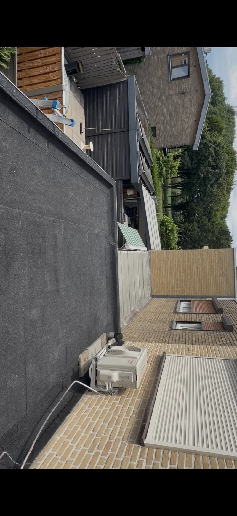 Bitumen dakbedekking naast woning met dakgoot